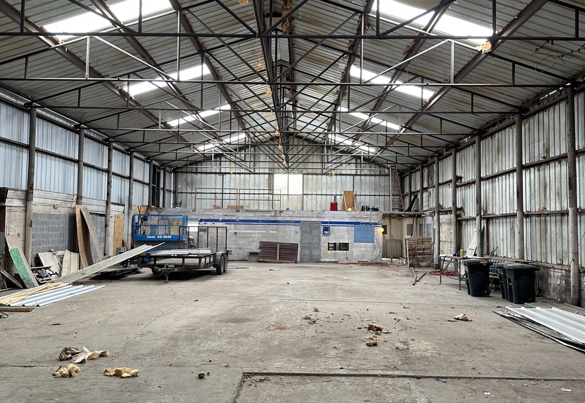 Out Of The Park before renovation, showing the open warehouse interior and steel roof trusses
